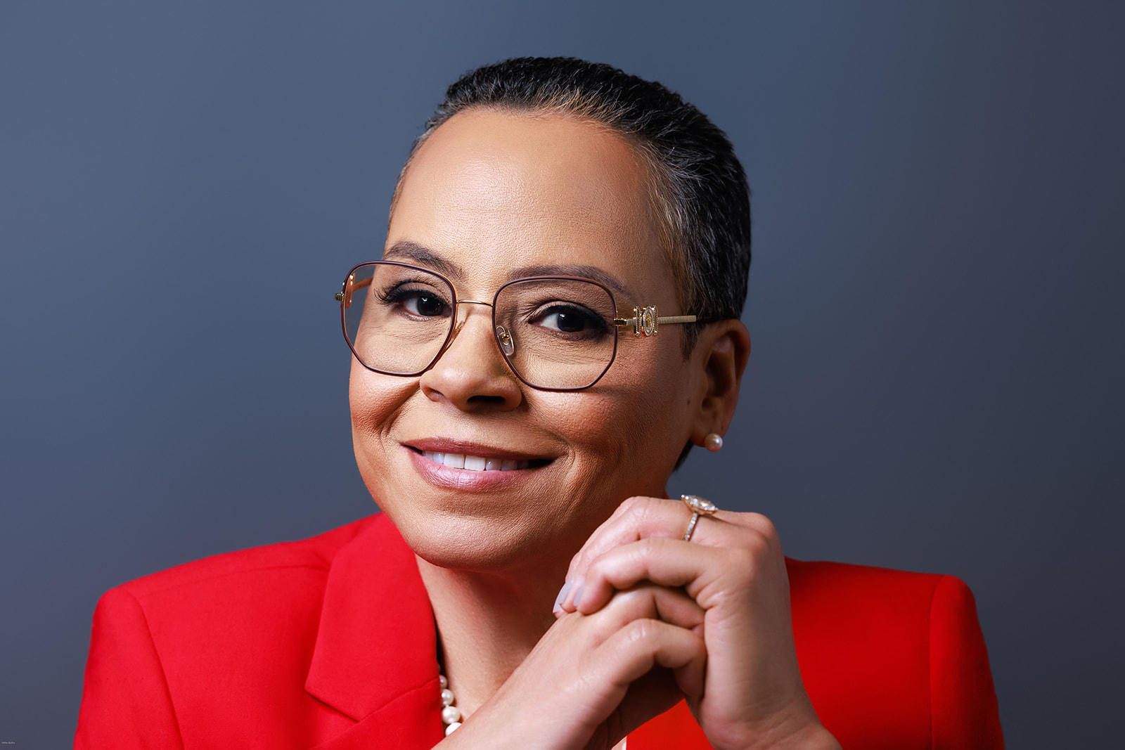 Smiling person wearing glasses and red blazer